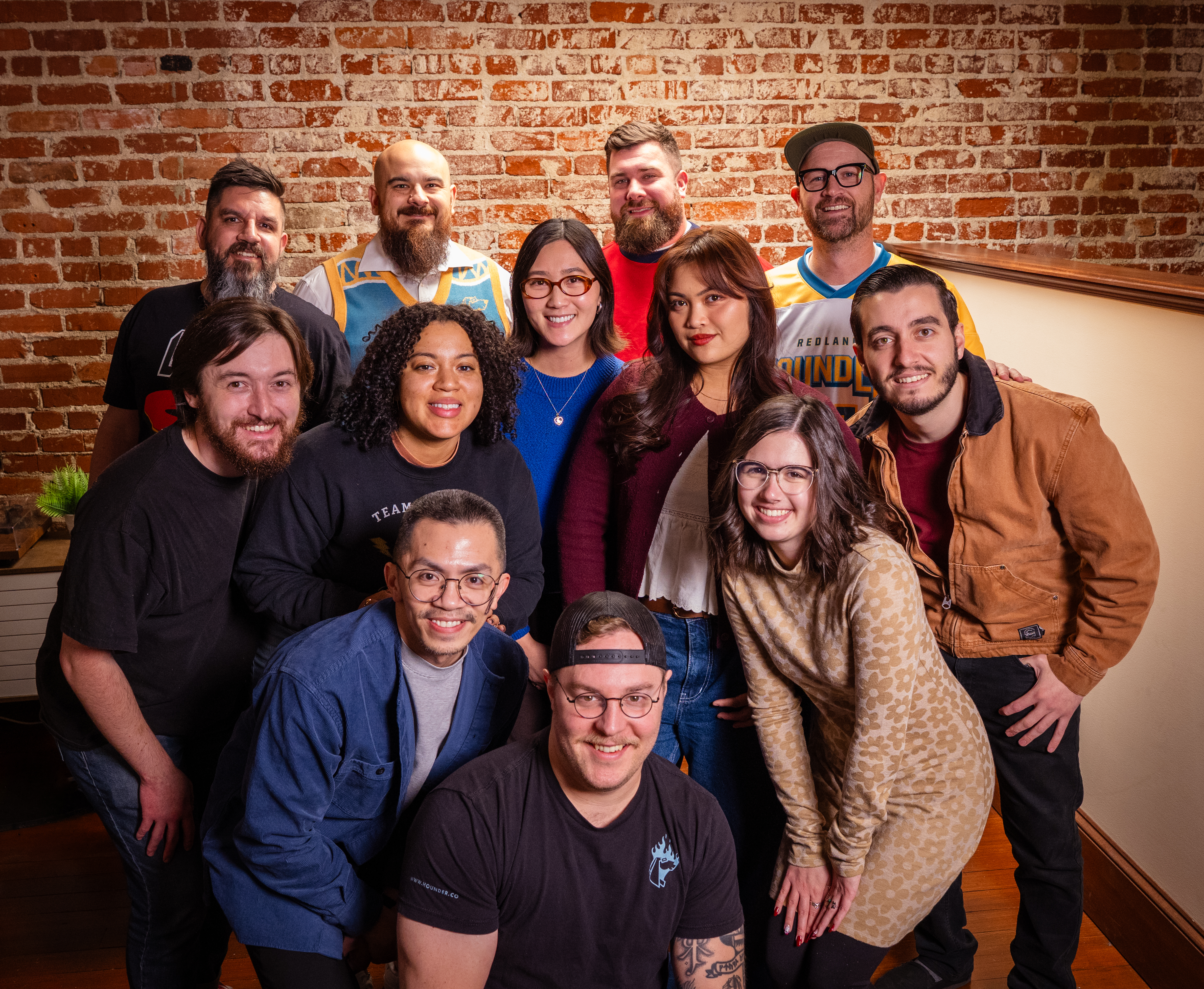 Entire Hounder Team smiling with a rustic brick wall background.