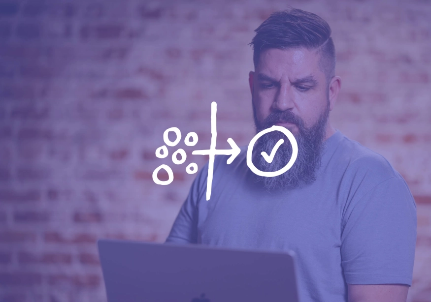 Man with a beard focused on a laptop with graphics overlay.