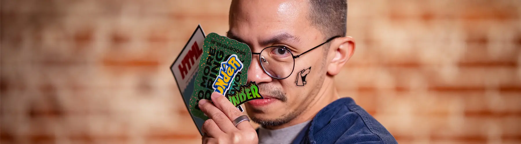 Man holds Pokémon cards, smiling, with a blurred brick wall background.