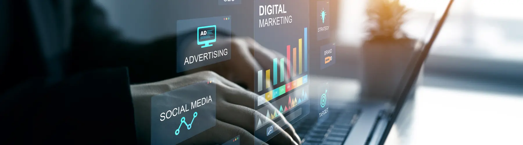 Hands typing on a laptop with digital marketing graphics displayed.