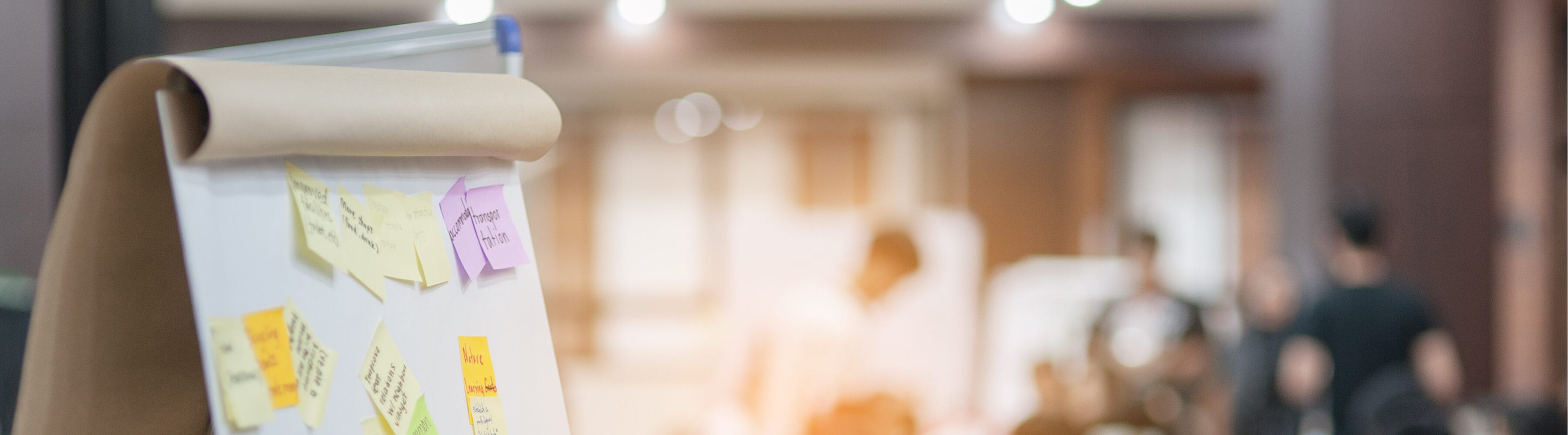 Flip chart with sticky notes, blurred office background.