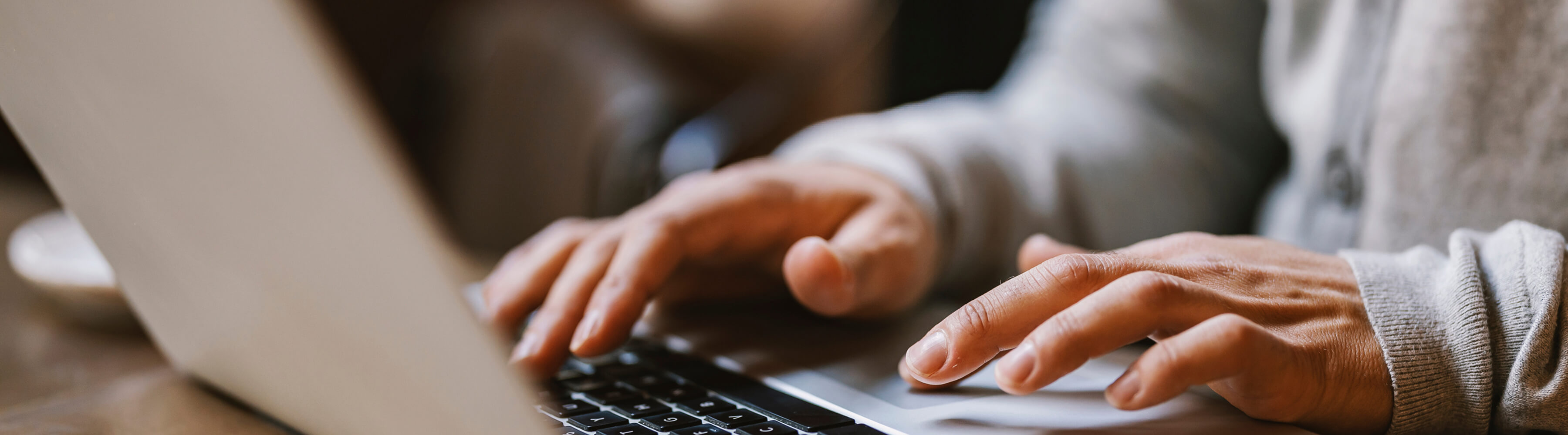Hands typing on a laptop keyboard.