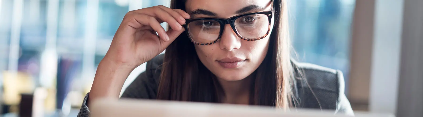 Woman with glasses focused on a computer screen.