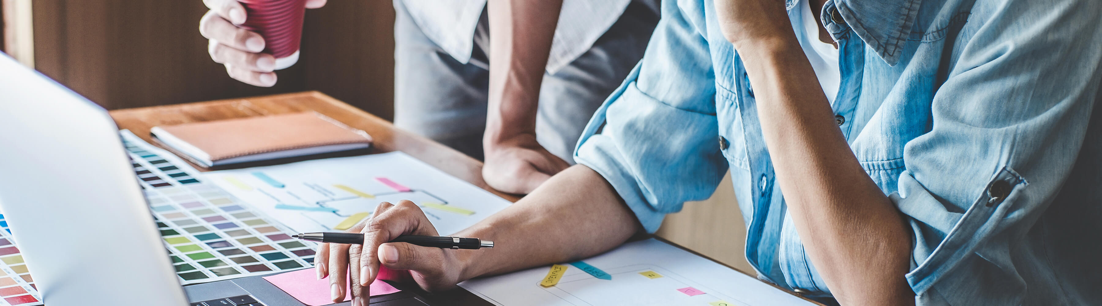 Team working on a project at a desk with laptop and charts.