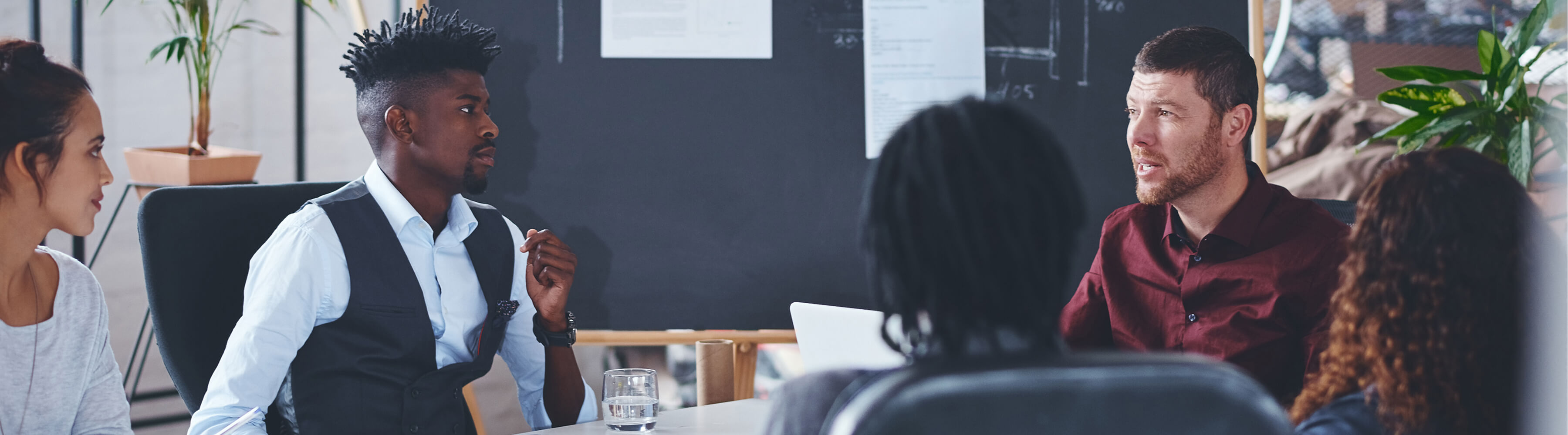 Team discussing at a table in a modern office setting.