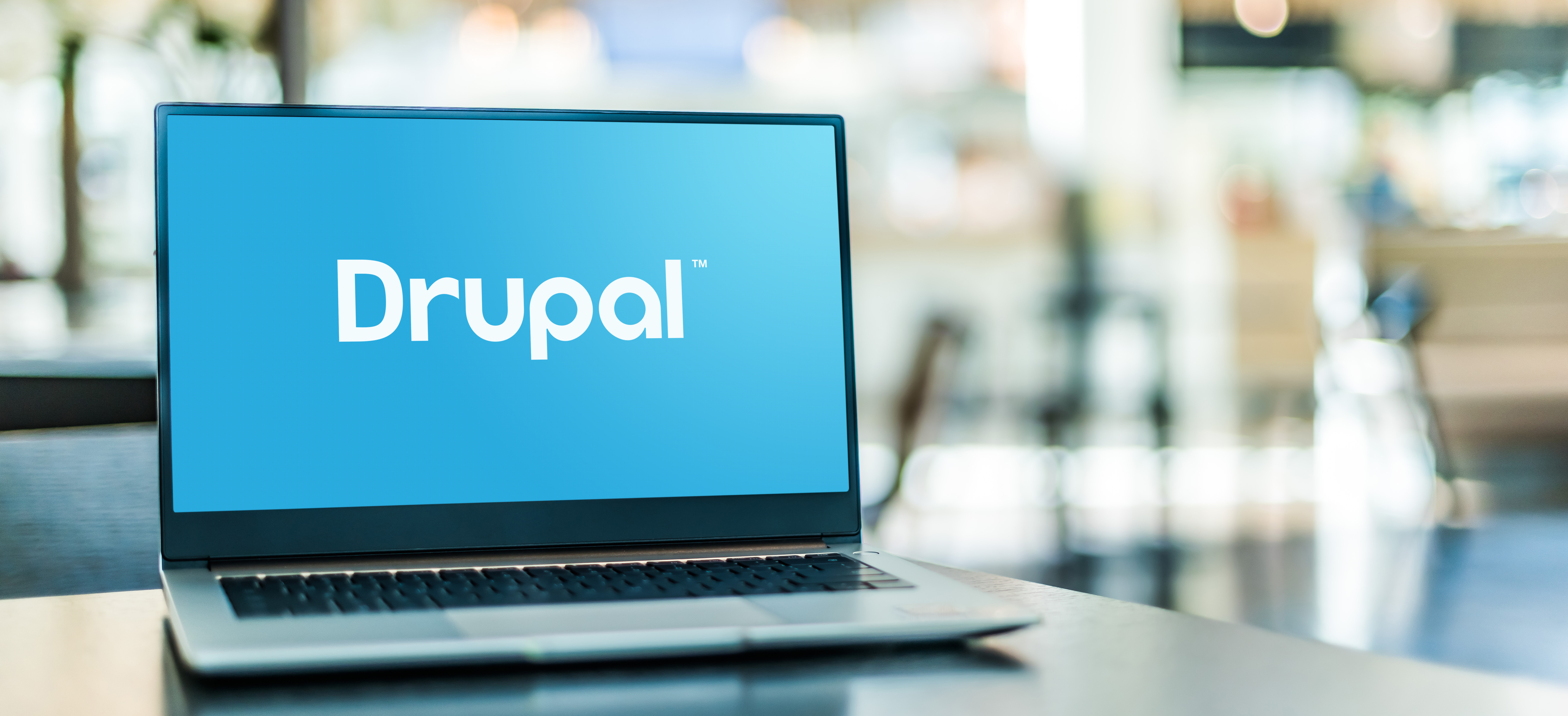 Laptop displaying Drupal logo on screen in a modern workspace.