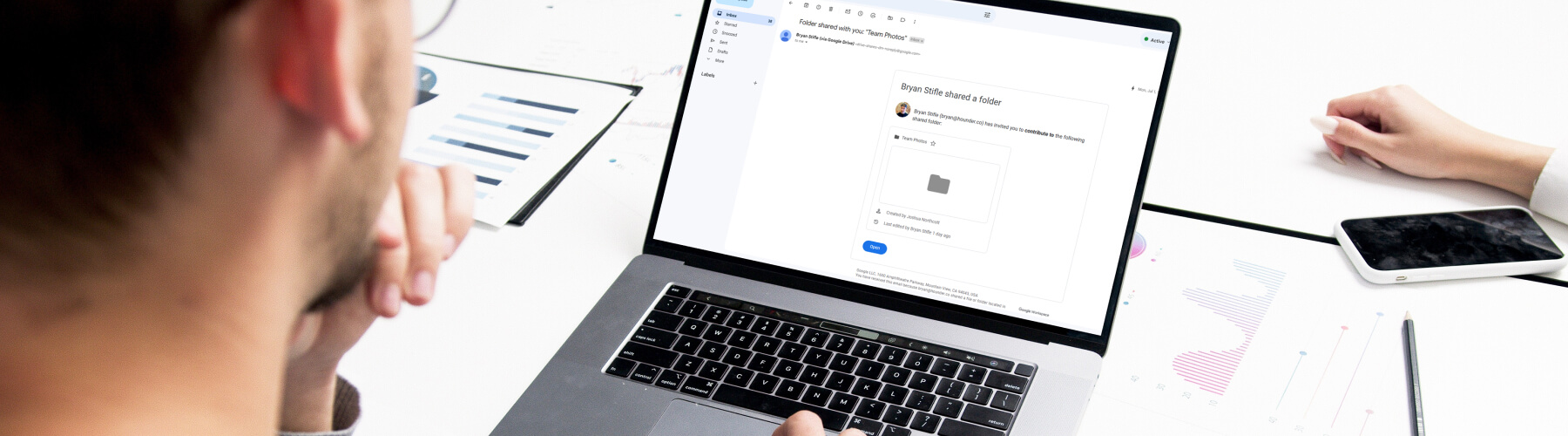 Person viewing shared folder on laptop in office environment.