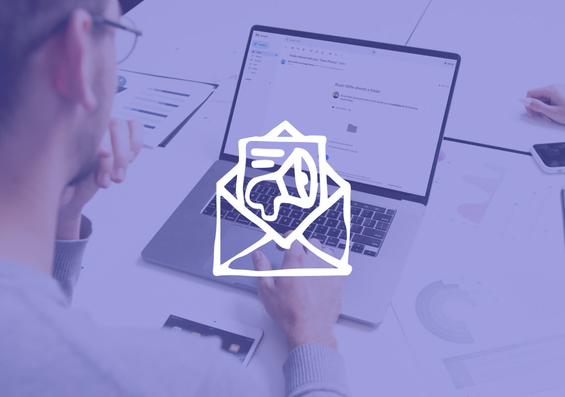 Man viewing folder share notification on laptop screen at work desk.