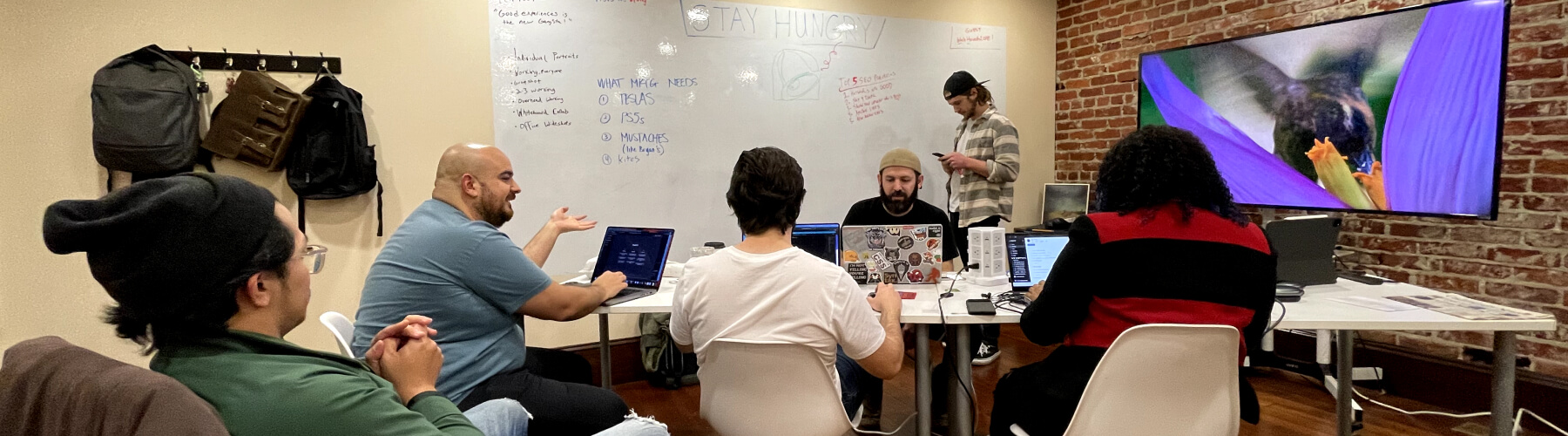 Team collaborating in a modern office with laptops and a whiteboard.