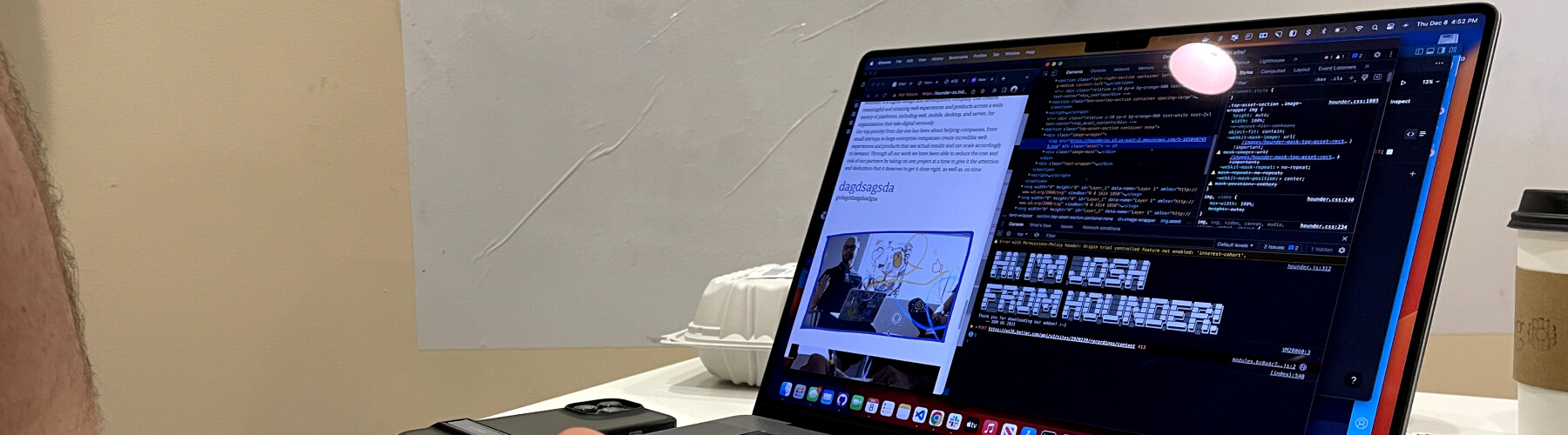 Developer coding on laptop with browser tools and coffee cup nearby.