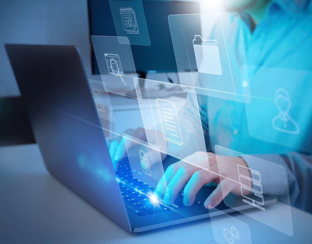 Person typing on laptop with digital document icons floating above.