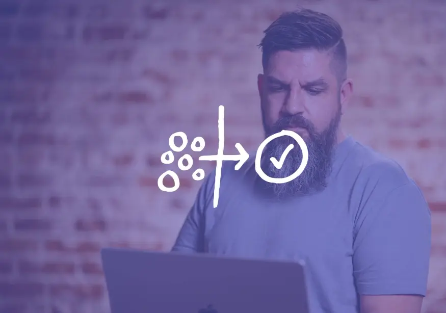 Man with a beard focused on a laptop with graphics overlay.