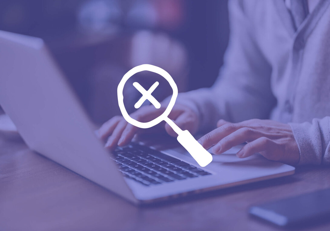 Hands typing on a laptop with a magnifying glass and cross icon overlay.