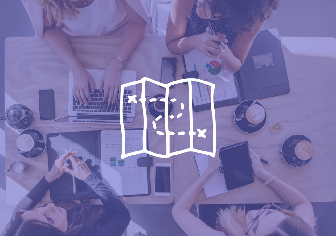 Top view of a team meeting with laptops and coffee on a wooden table.