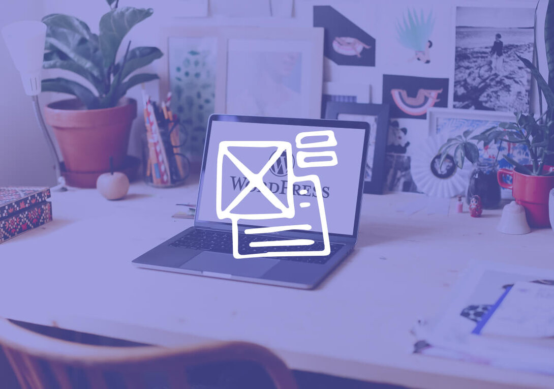 Laptop displaying WordPress logo on desk with decorative items.