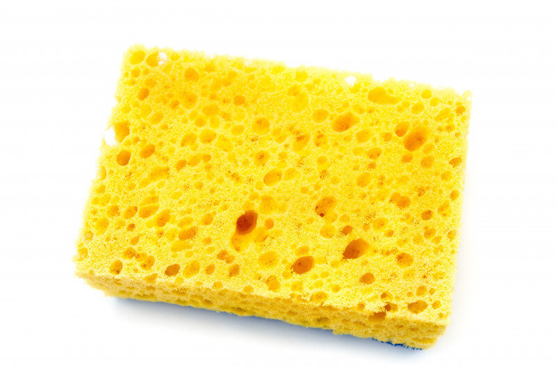Bright yellow kitchen sponge on a white background.